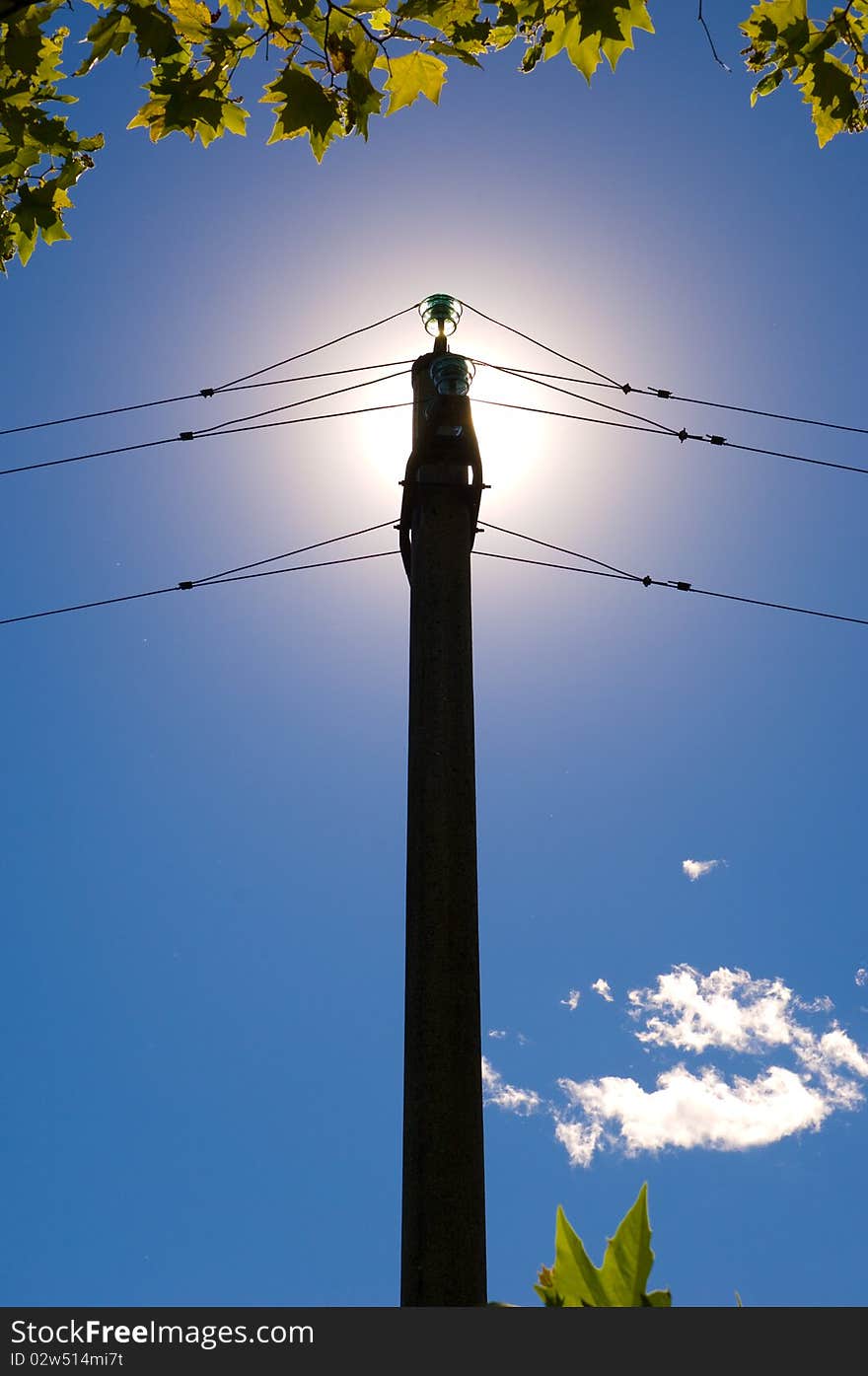 Electrical pylon over a blue sky and sun for green energy