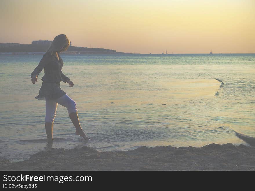 At sunset, the girl walks on the beach