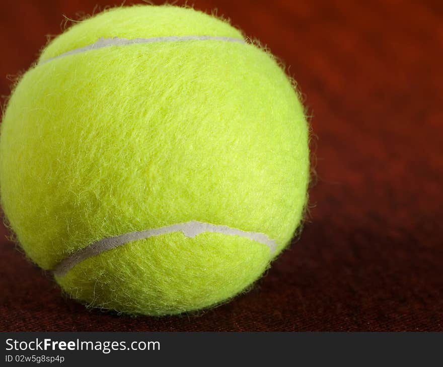 Tennis ball on the orange surface, closeup shot, for various, tennis,recreation and sport themes