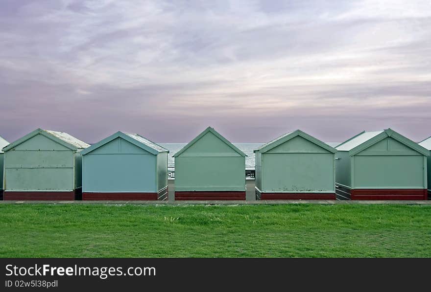 A voew of the back of beach huts with grass and sky