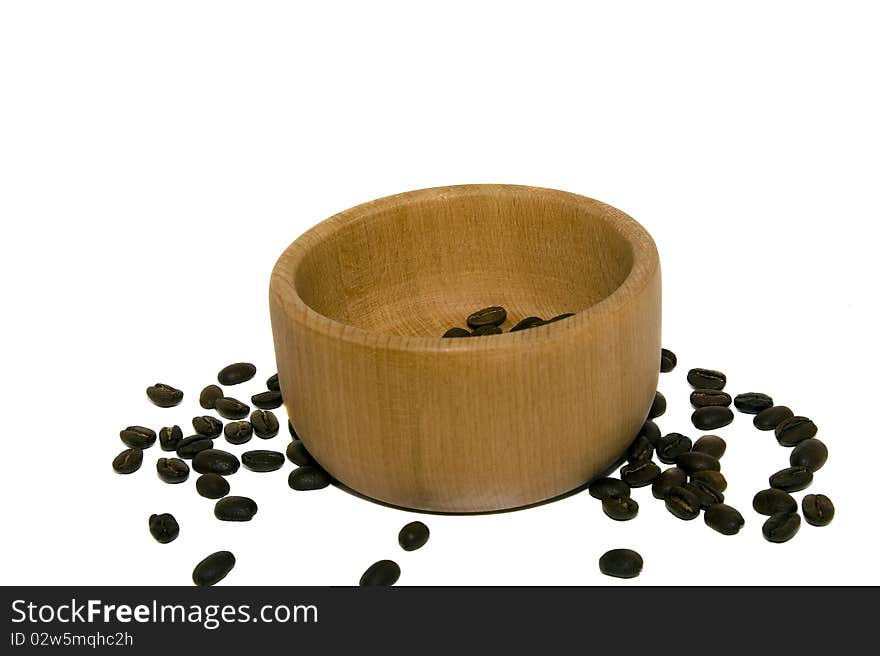 The grains of coffee scattered near a wooden bowl. The grains of coffee scattered near a wooden bowl