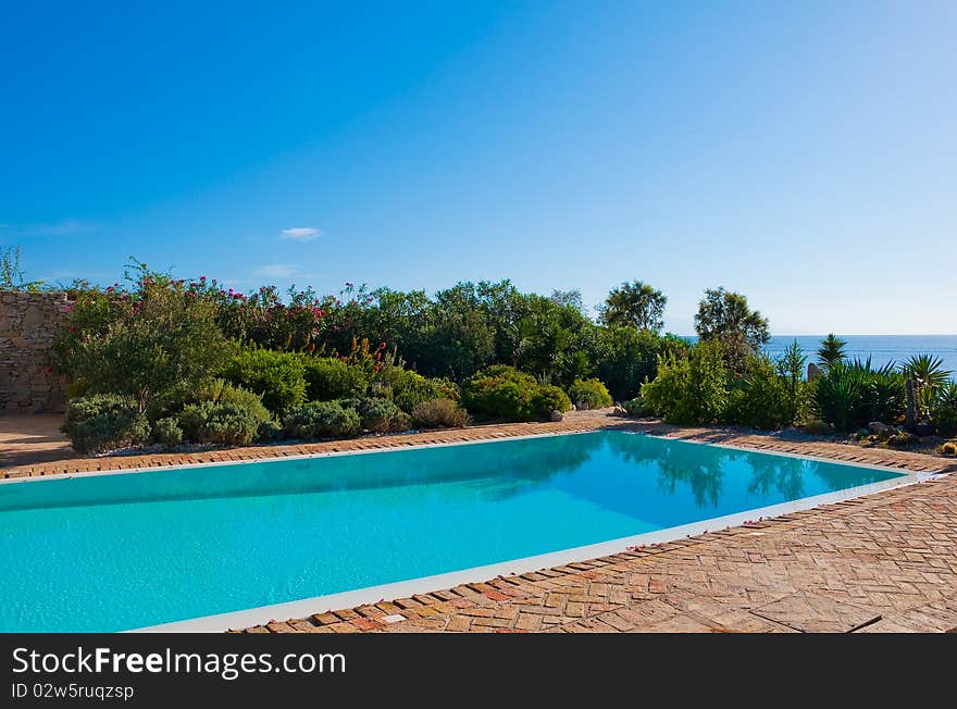 Blue pool in the yard against the sea