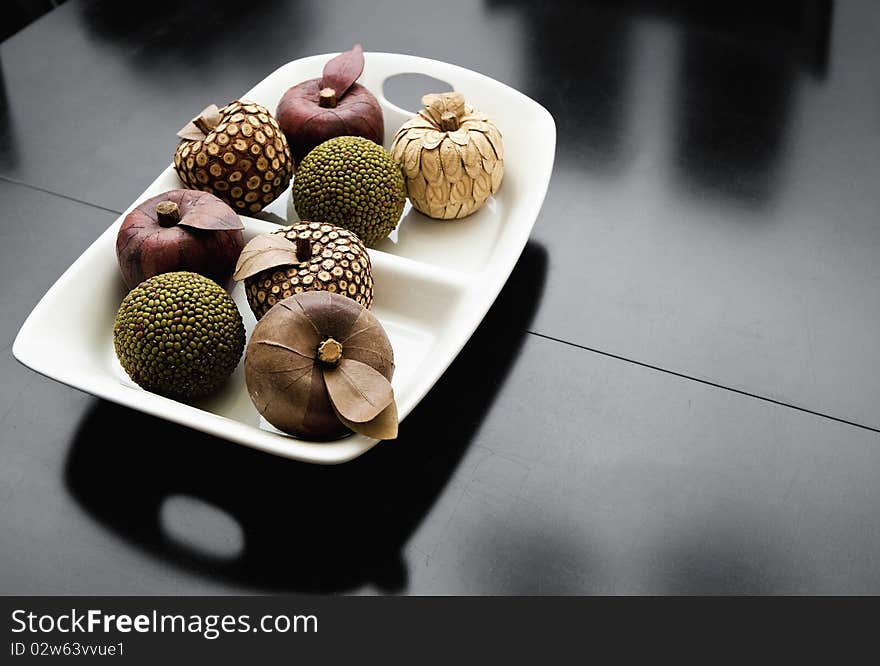 Wooden display fruit sit in a white bowl. Wooden display fruit sit in a white bowl