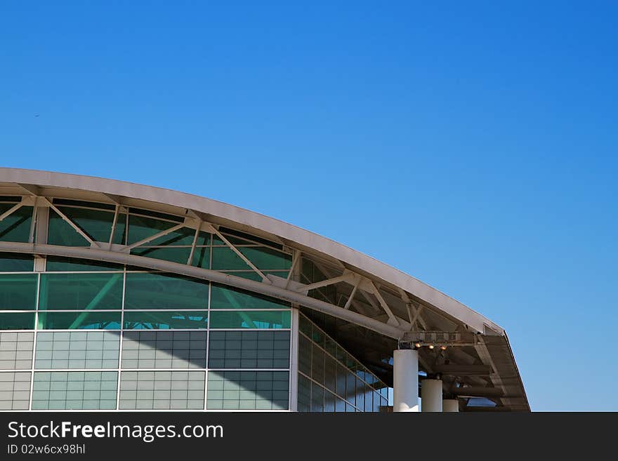 Arched roof sports complex building aginst a cloudless blue sky. Arched roof sports complex building aginst a cloudless blue sky