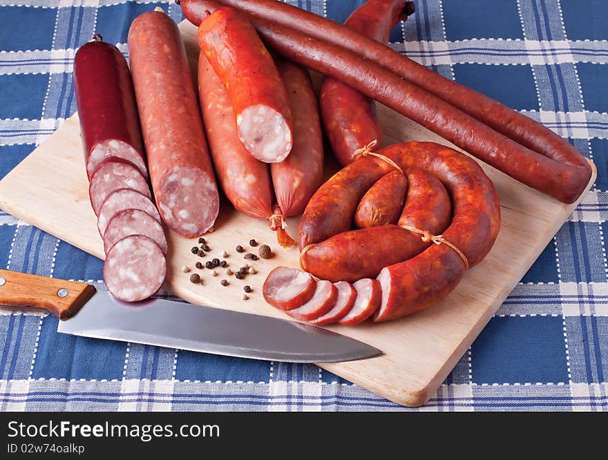 A variety of processed cold meat products, on a wooden cutting board. A variety of processed cold meat products, on a wooden cutting board.