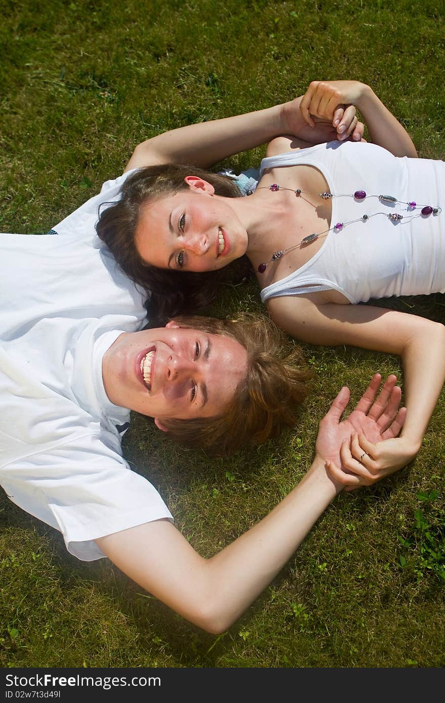 Young couple enjoying a sunny day in the grass. Nice lively image. Young couple enjoying a sunny day in the grass. Nice lively image.