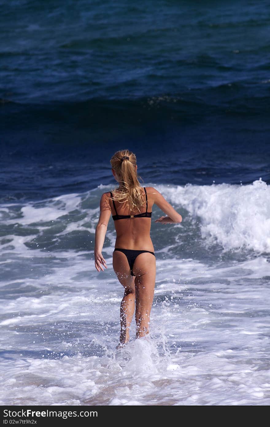 Beautiful young woman playing with waves on the ocean beach. Beautiful young woman playing with waves on the ocean beach