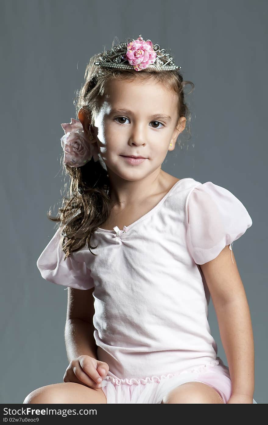 Young cute girl princess in lace dress and pink ribbon against grey background. Young cute girl princess in lace dress and pink ribbon against grey background