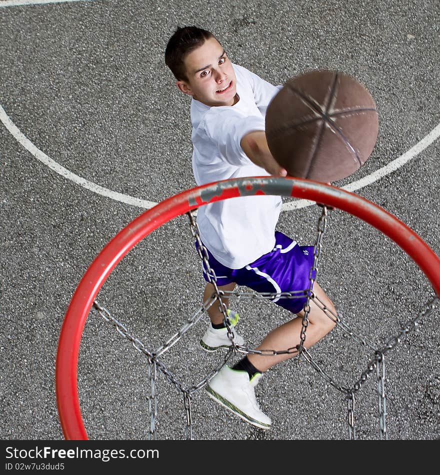 Young basketball player on the street going to the hoop. Great angle from above. Young basketball player on the street going to the hoop. Great angle from above.