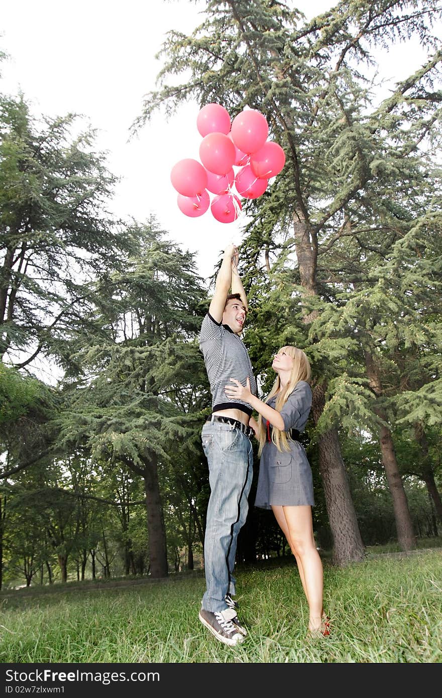 Boy is flying away with balloons, girl is holding him. Boy is flying away with balloons, girl is holding him