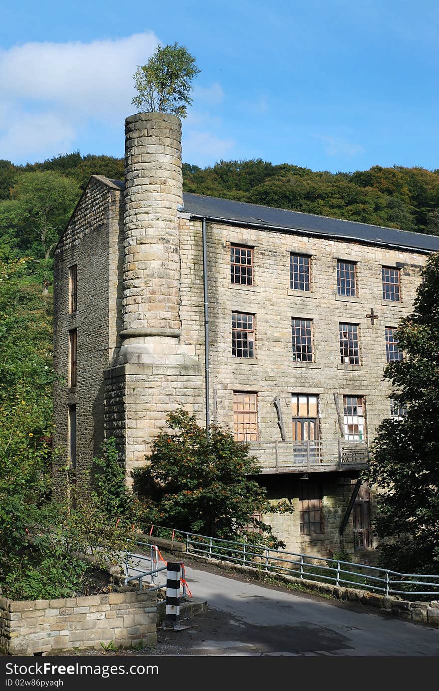 Old textile mill with tree growing out of the chimney in West Yorkshire. Old textile mill with tree growing out of the chimney in West Yorkshire