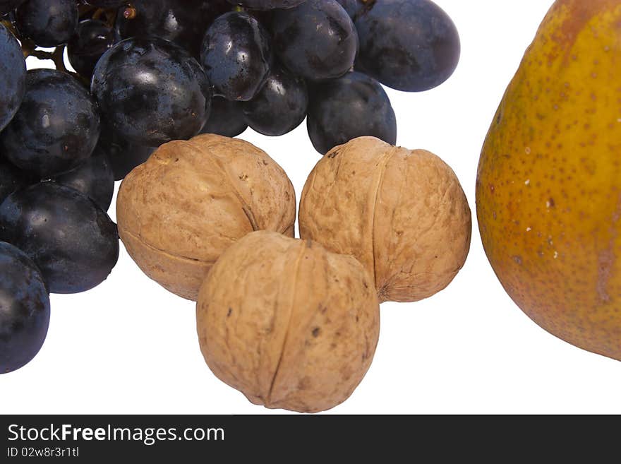 A bunch of grapes, three walnuts and a pear isolated on white background. A bunch of grapes, three walnuts and a pear isolated on white background