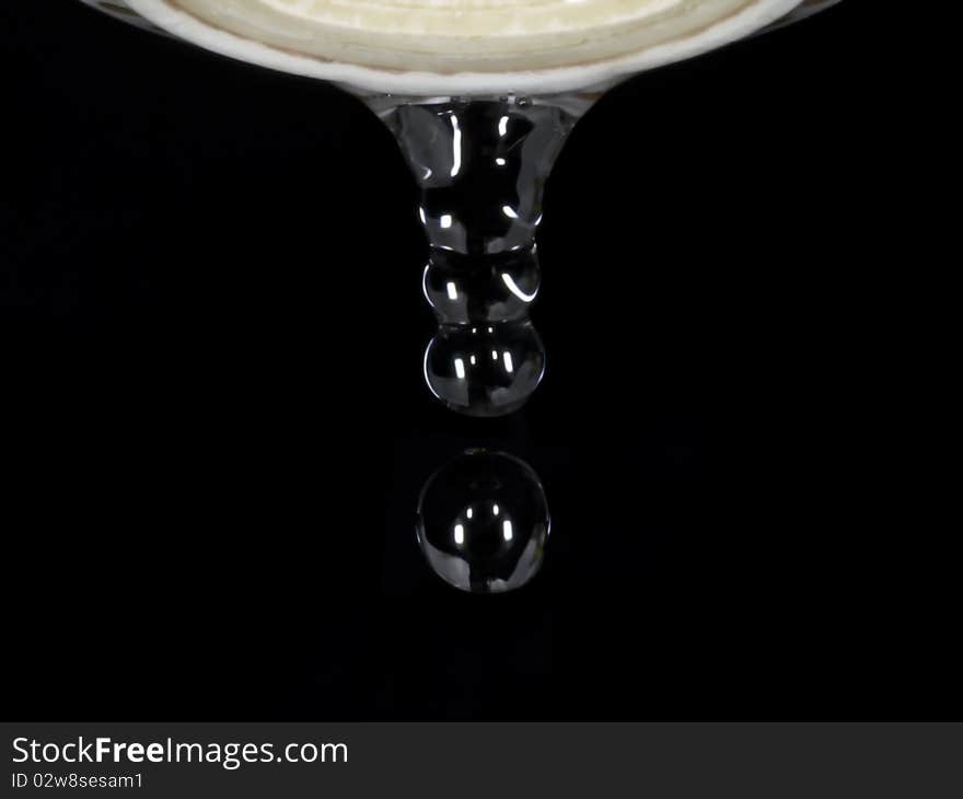 Drops of water coming out of old leaking faucet against black background