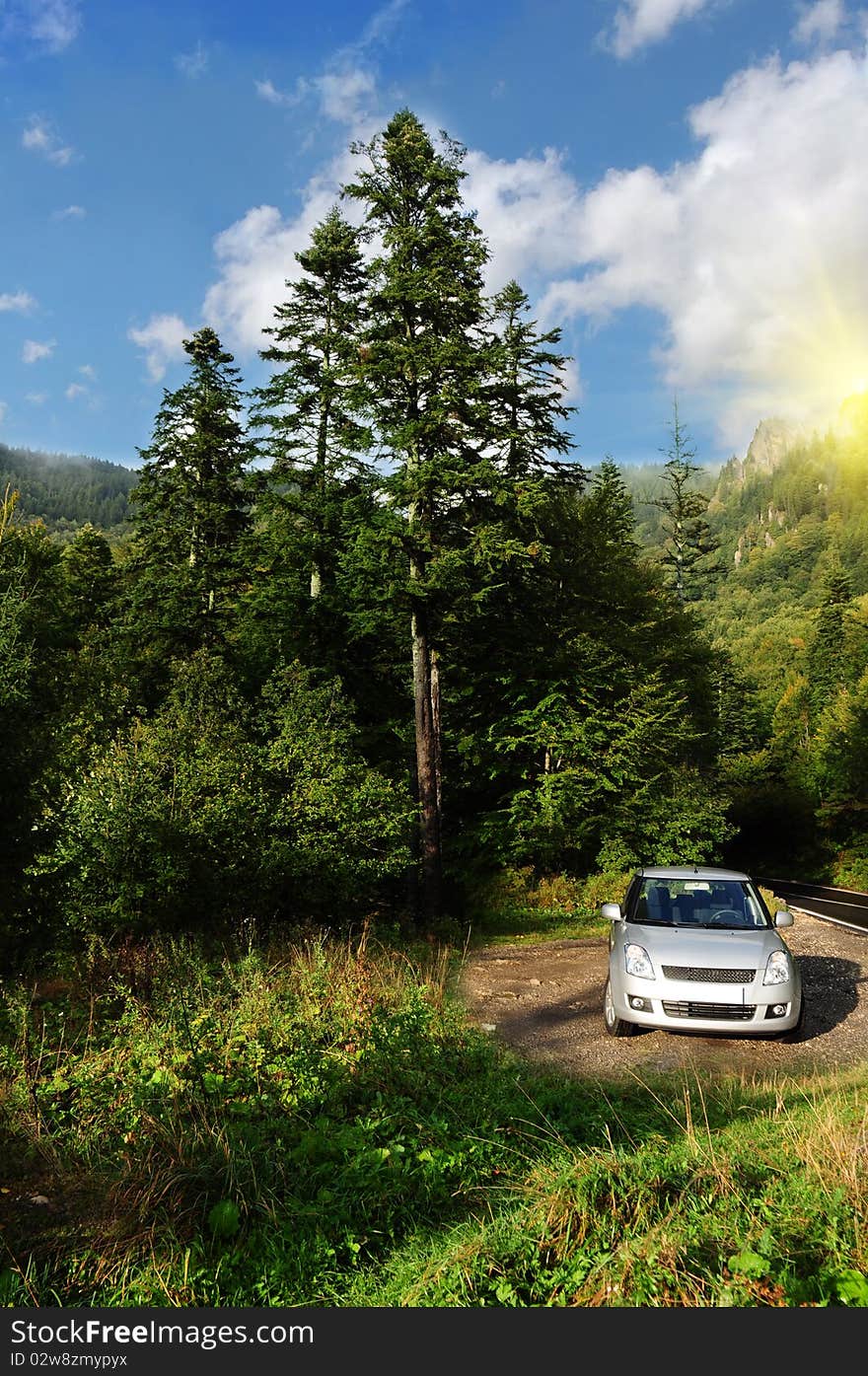 Relaxing scenery with a small silver car parked high in the mountains. It is a clear sunny summer day. Mountain tourist travel. Relaxing scenery with a small silver car parked high in the mountains. It is a clear sunny summer day. Mountain tourist travel.