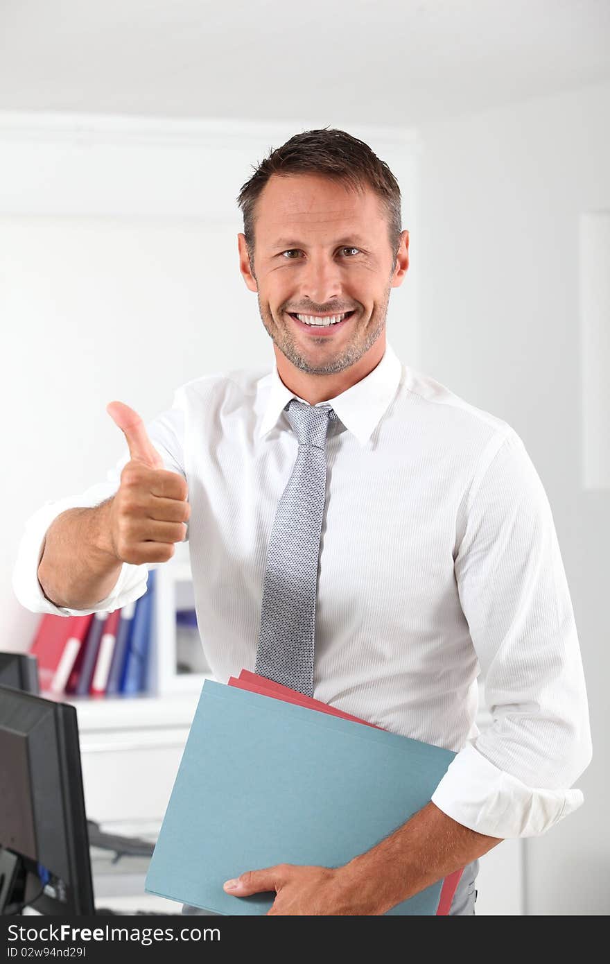 Happy businessman with thumb up in the office. Happy businessman with thumb up in the office