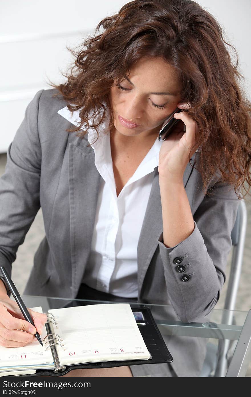 Businesswoman on the phone writing on agenda. Businesswoman on the phone writing on agenda