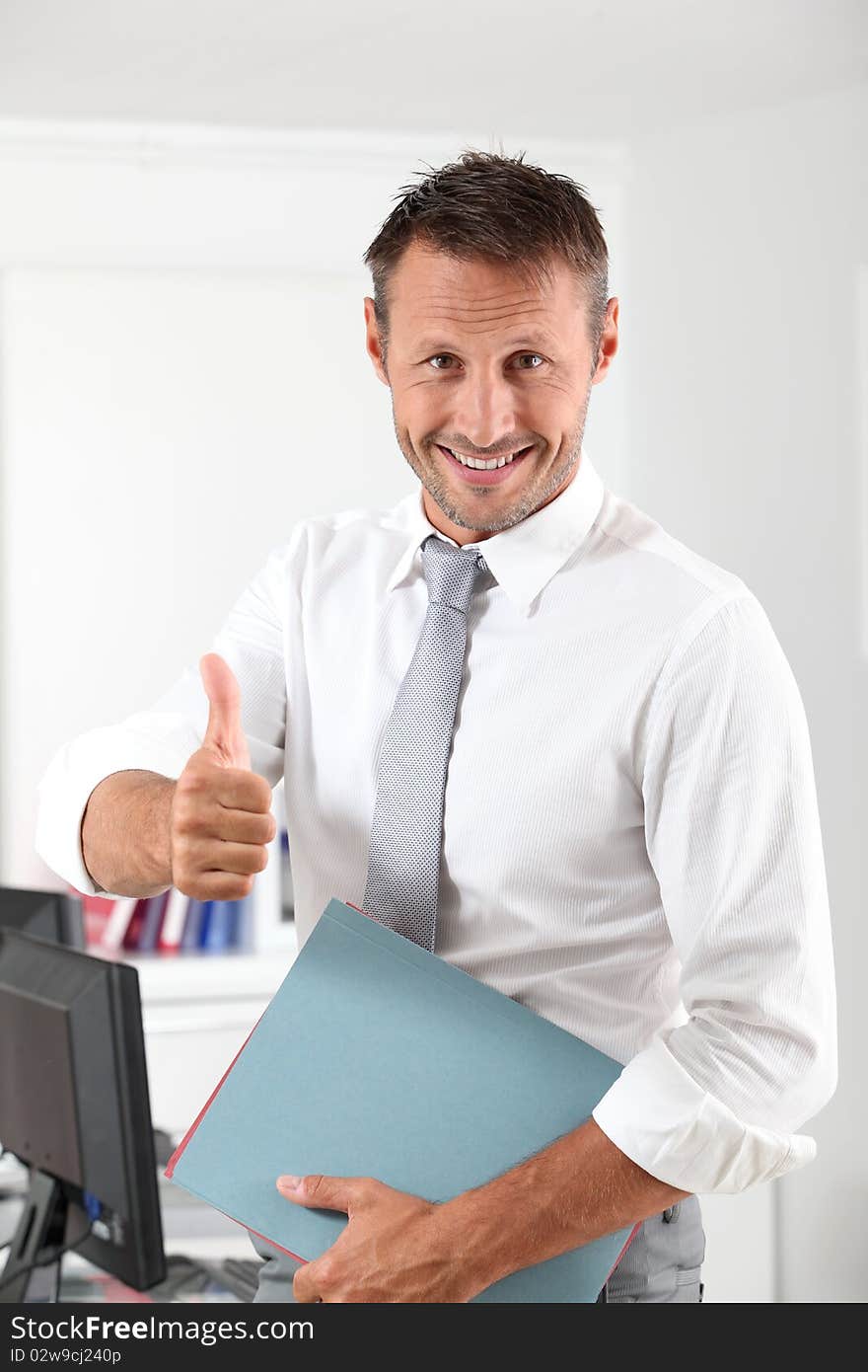 Happy businessman with thumb up in the office. Happy businessman with thumb up in the office