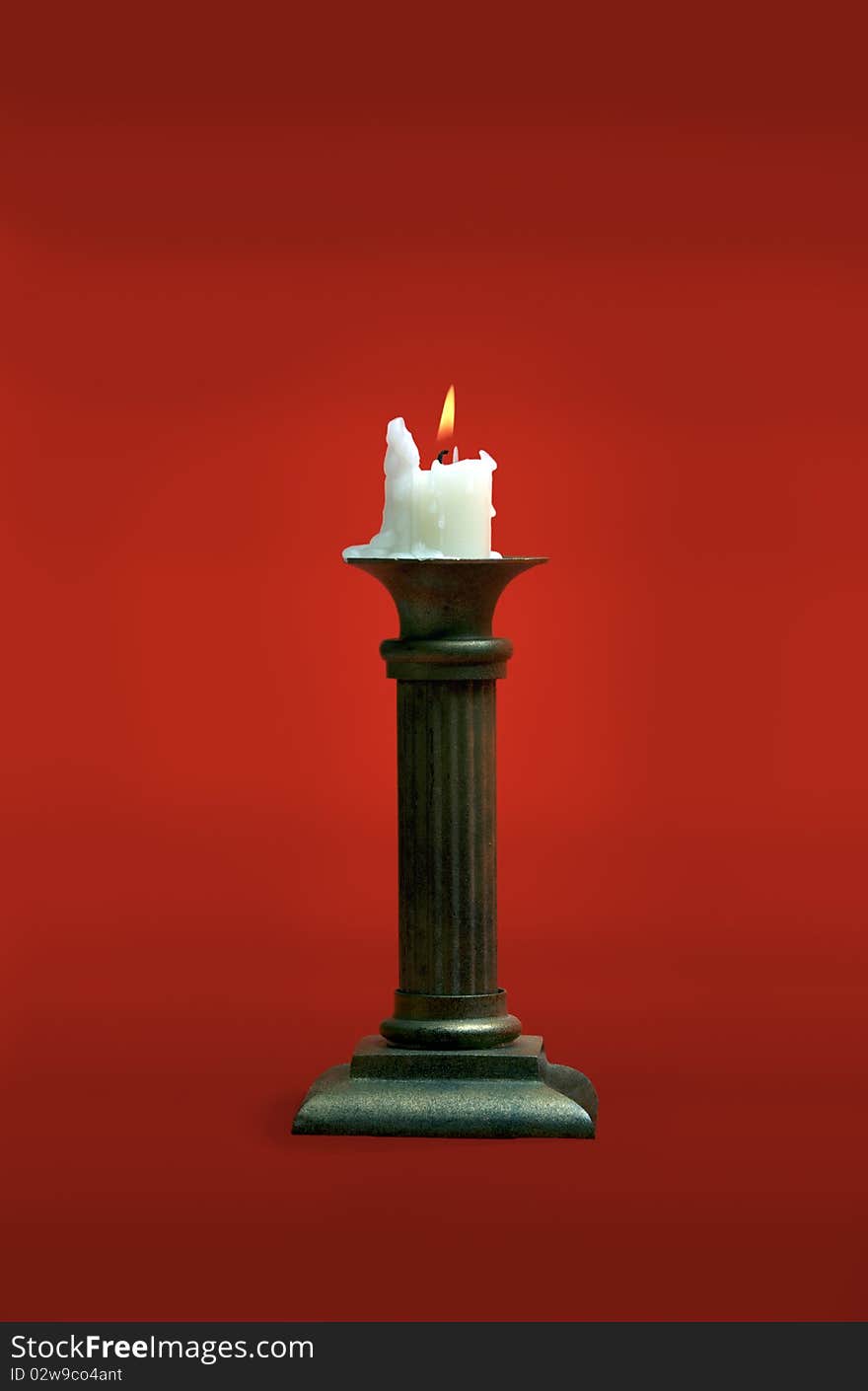 Candle burning in the old candlesticks on a red