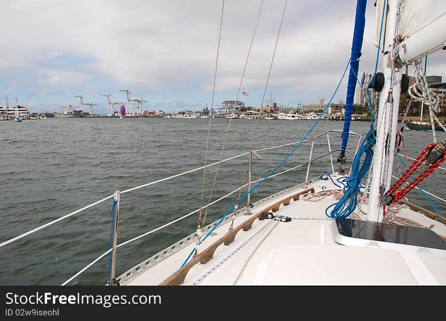 A sloop under way with the main sail only near the San Francisco Bay with Jack London Square in the background. A sloop under way with the main sail only near the San Francisco Bay with Jack London Square in the background