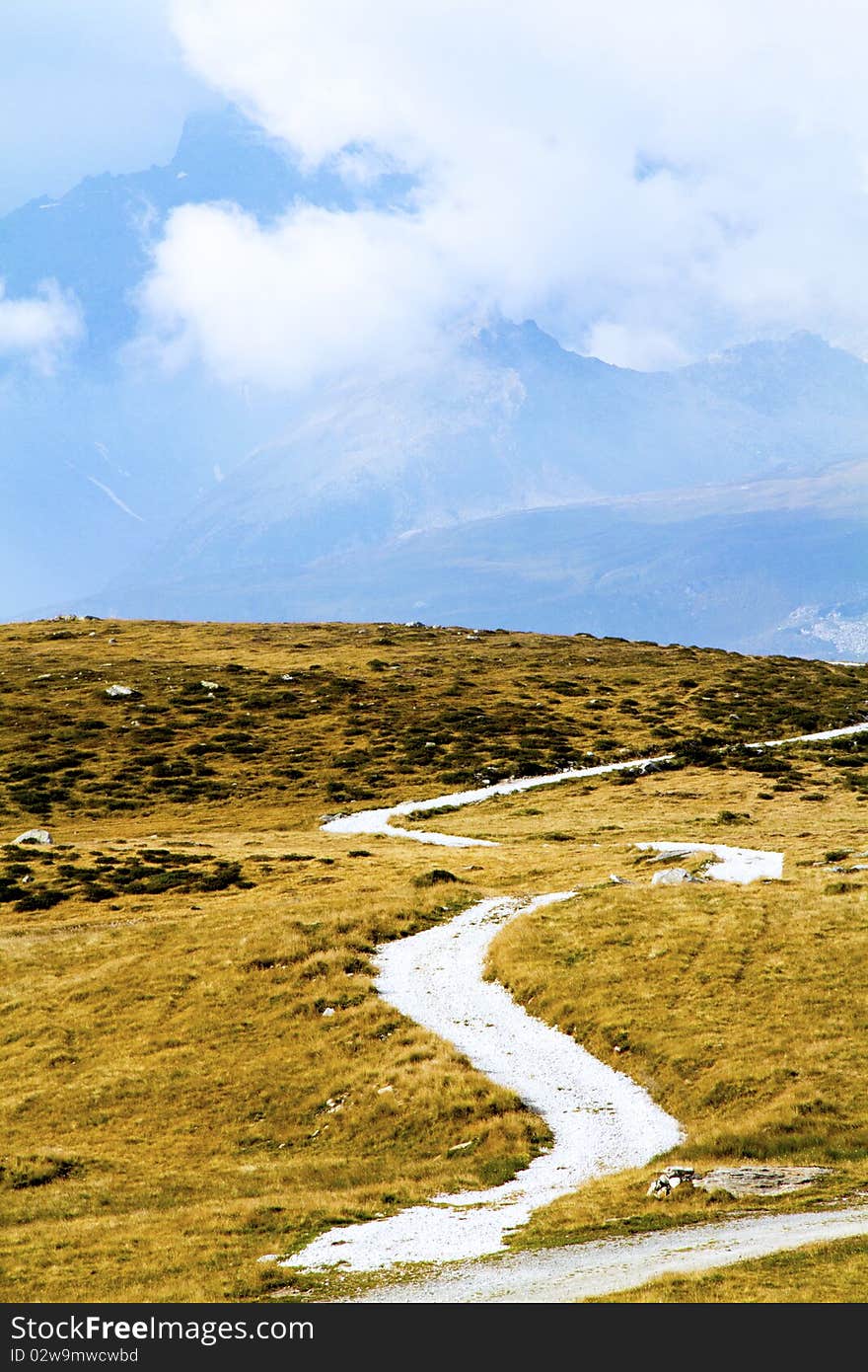 Mountain road between pastures and cloudy sky. Mountain road between pastures and cloudy sky