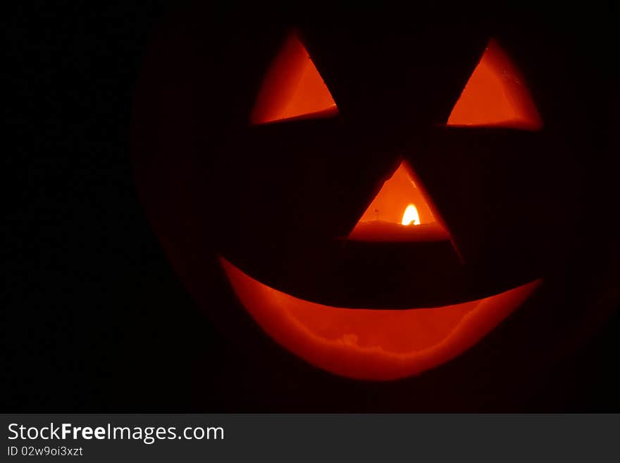 Jack o'lantern glowing on black background with space for text