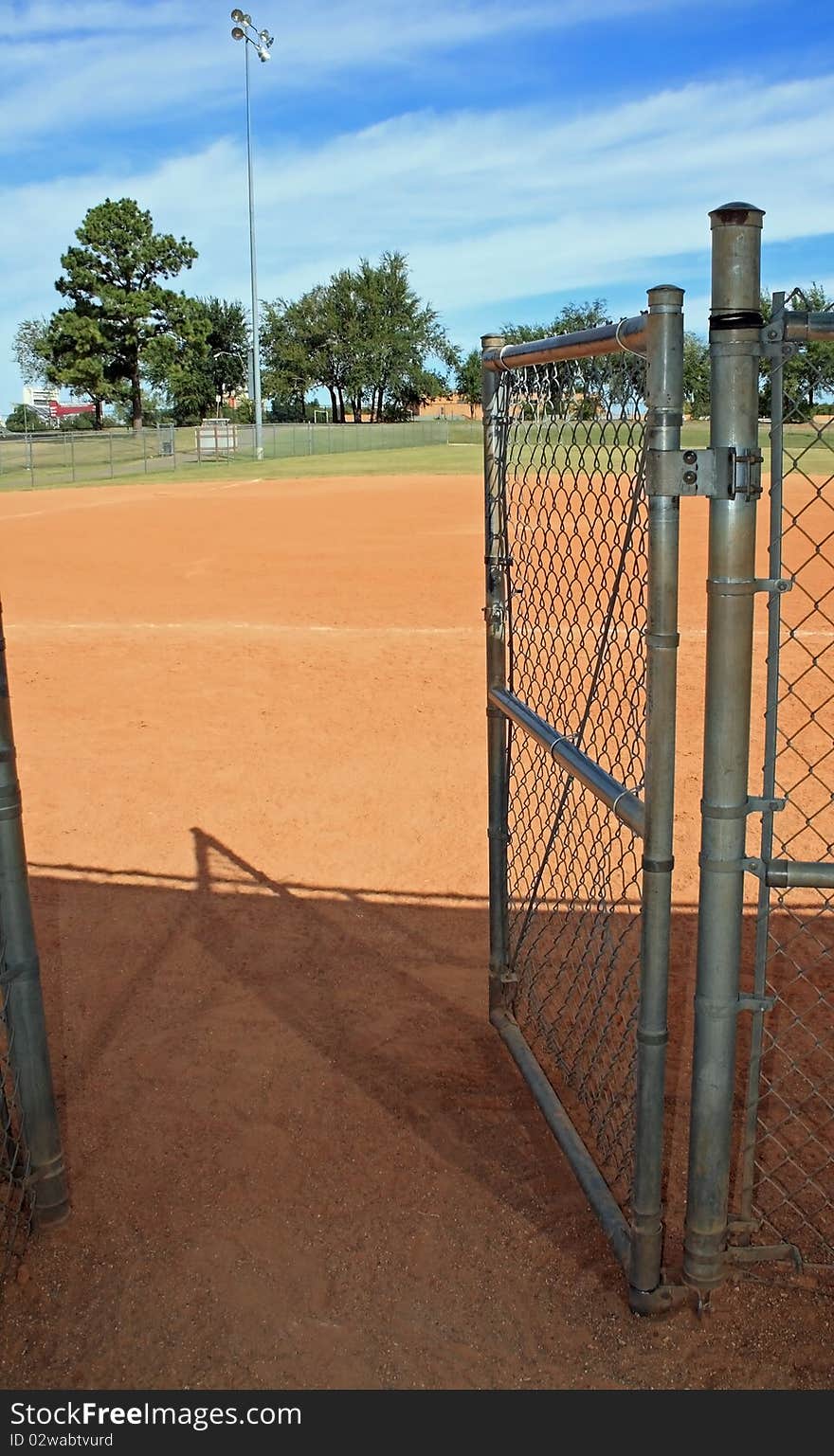 A chain link gate at city baseball park exiting dugout going out. A chain link gate at city baseball park exiting dugout going out.