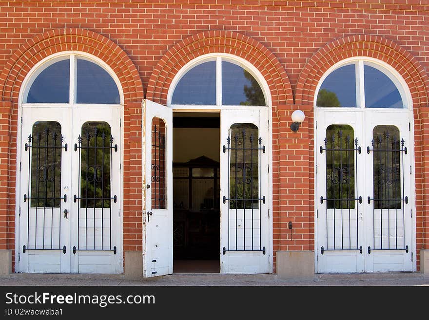 Three doors on an historic brick building, the center door is open.