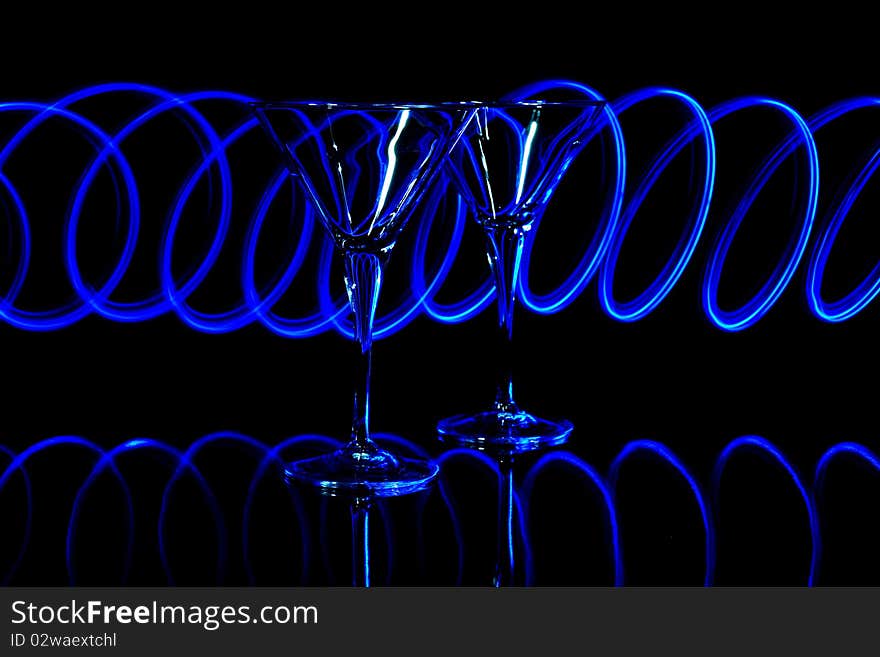 A pair of martini glasses lit with blue led light trails. A pair of martini glasses lit with blue led light trails