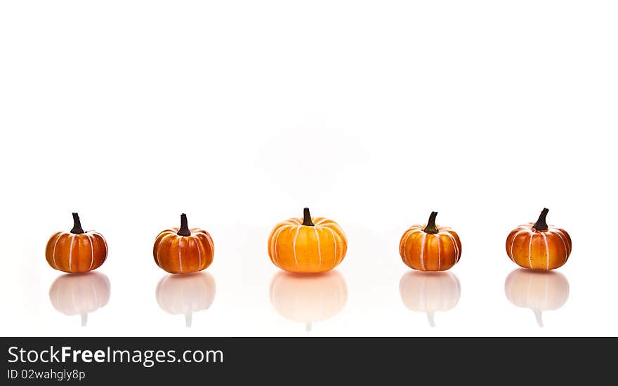 Small pumpkins in a row on a a white background. Small pumpkins in a row on a a white background.