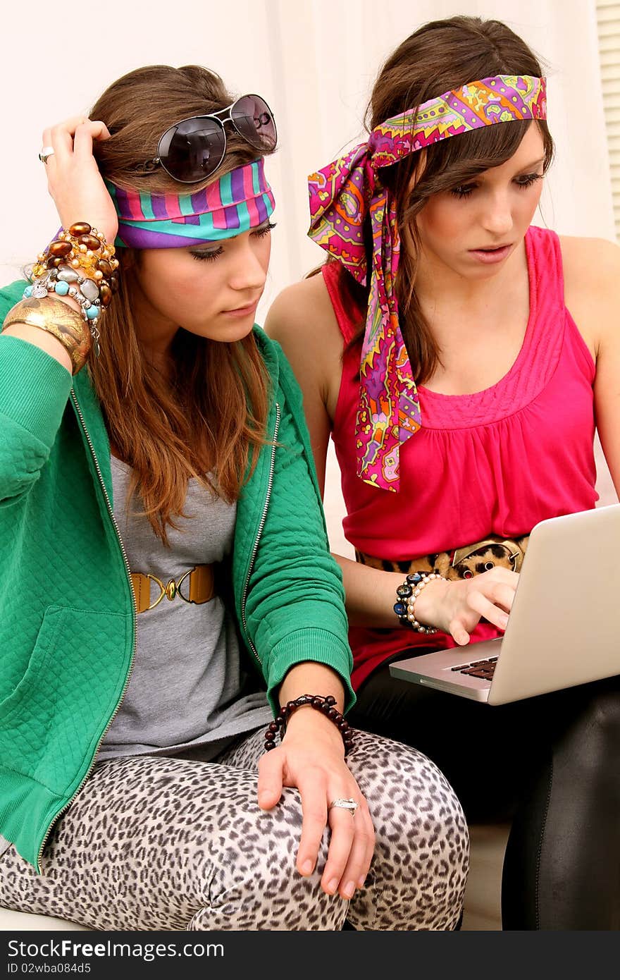 Two girls dressed in hippie style with a laptop. Two girls dressed in hippie style with a laptop