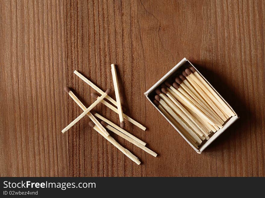 Few matches near matchbox on wooden background