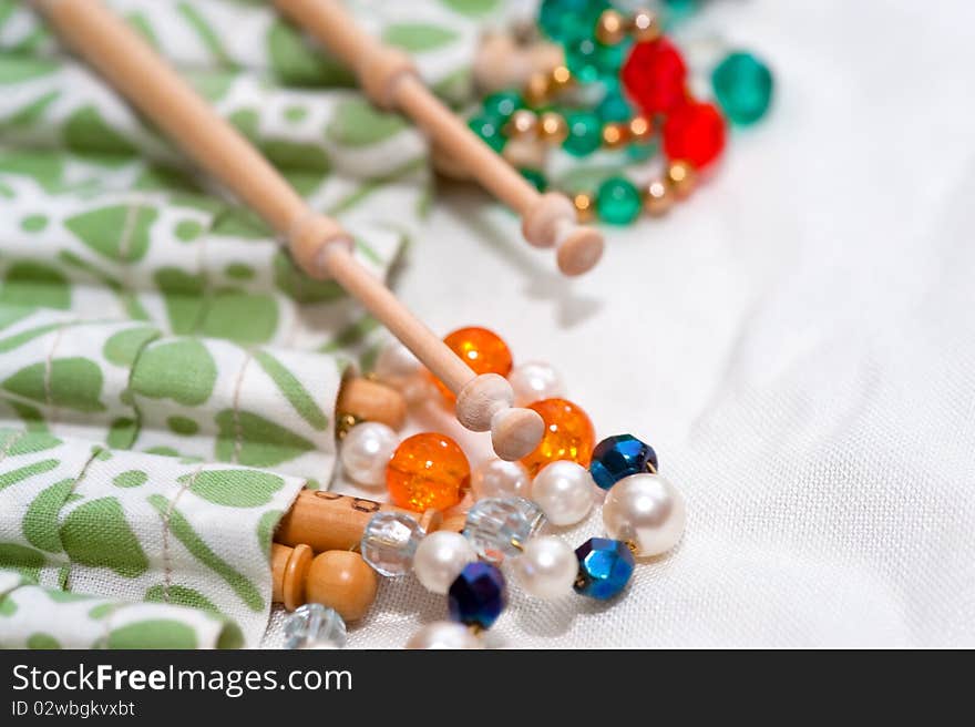 Wooden lace making bobbins and decorative beads on white linen. Wooden lace making bobbins and decorative beads on white linen