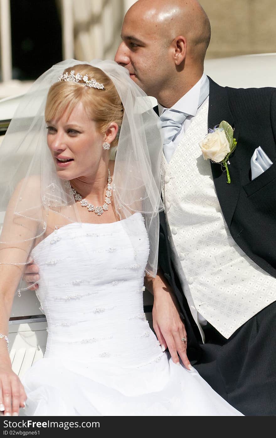 A stunning looking bride and groom next to a vintage wedding car