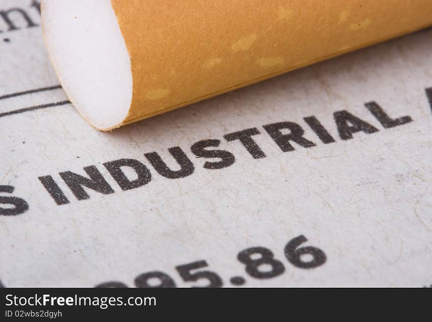 A filtered cigarette laying on a newspaper next to the word industrial.