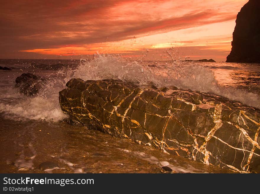 The setting sun lights up the beach at Crackington Haven, Cornwall as a wave gently breaks over a rock. The setting sun lights up the beach at Crackington Haven, Cornwall as a wave gently breaks over a rock.