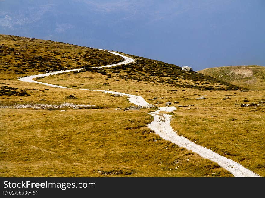 Mountain road between pastures and cloudy sky. Mountain road between pastures and cloudy sky