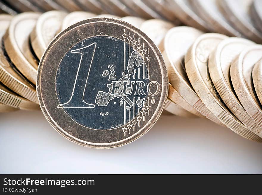 Single Euro leaning against stacks of coins, isolated on white background. Single Euro leaning against stacks of coins, isolated on white background.