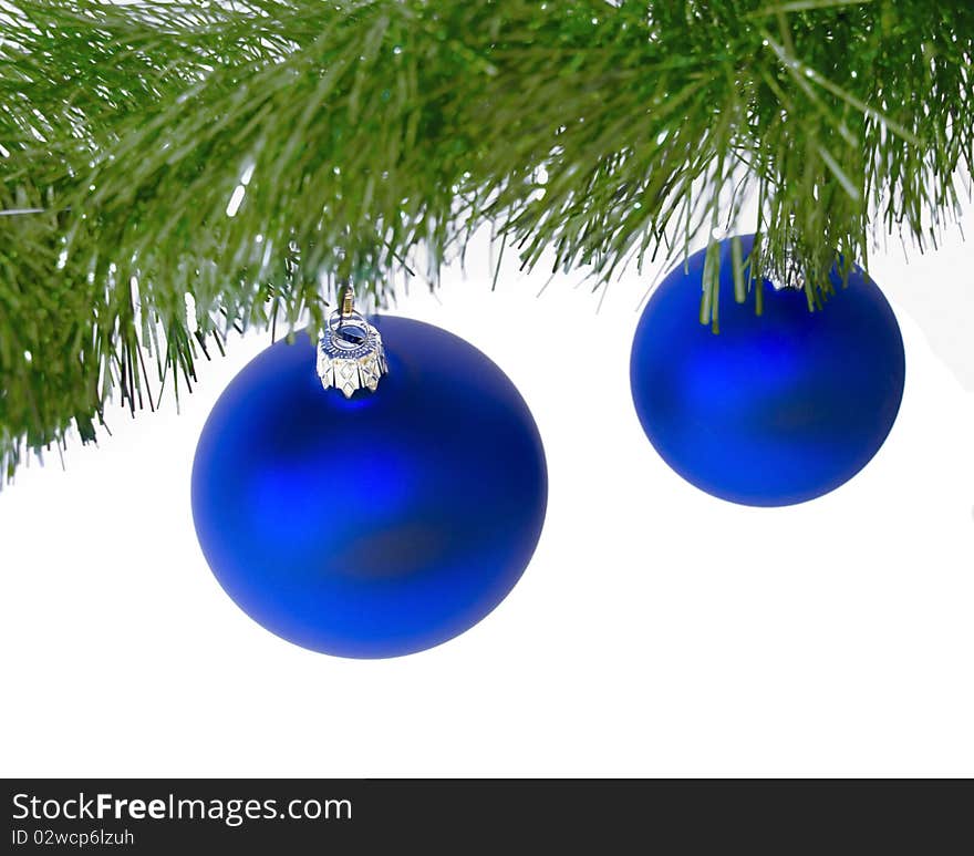 Two blue christmas ball hanging on w green christmas tree branch, against a wjite background. Two blue christmas ball hanging on w green christmas tree branch, against a wjite background