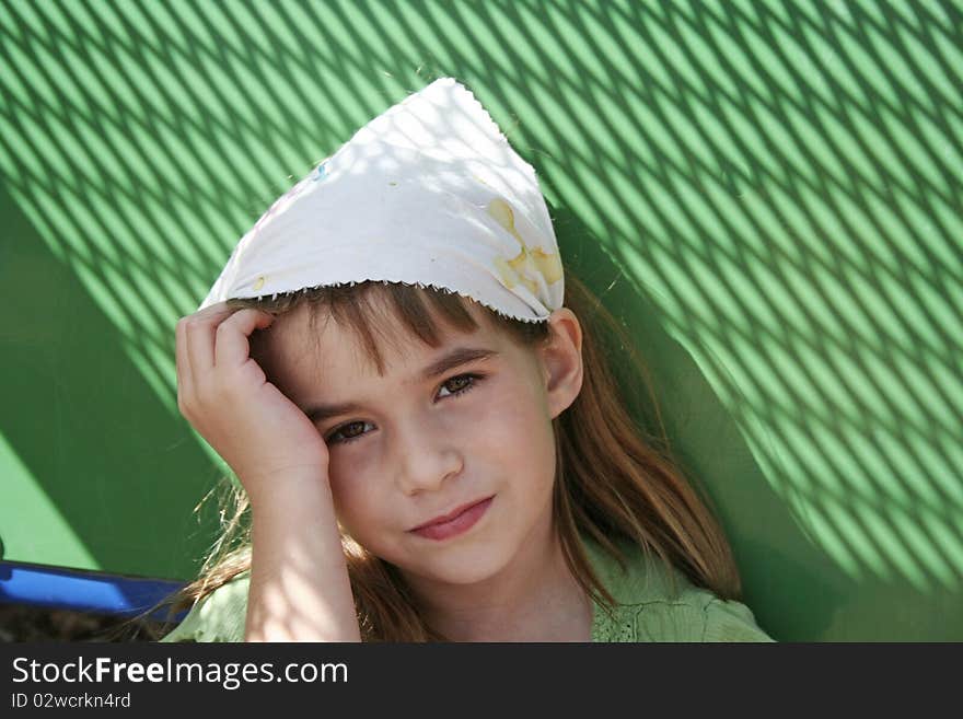 Sad little girl with green background wearing kerchief staring into camera