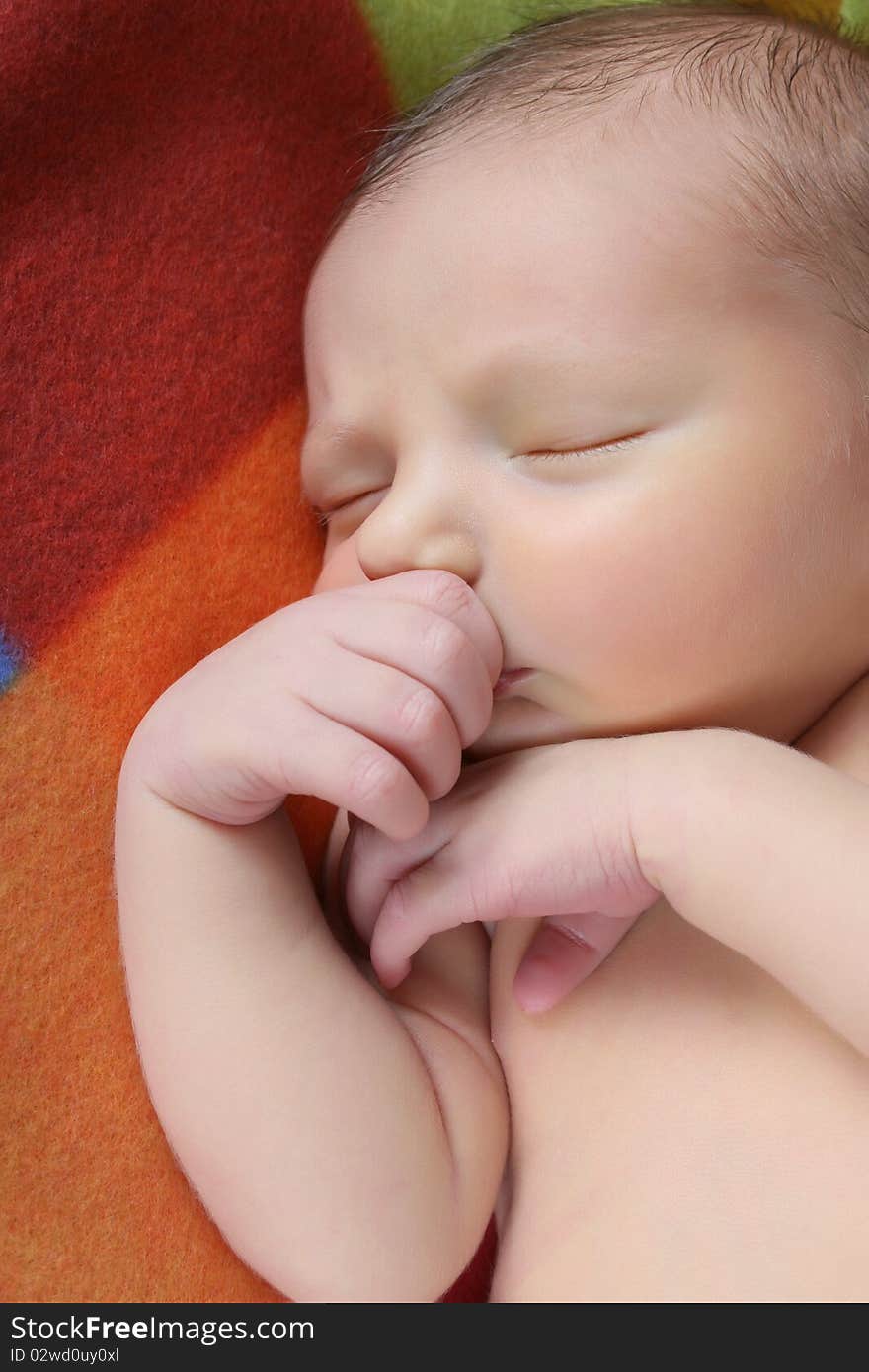 Newborn baby boy lying on a colorful blanket