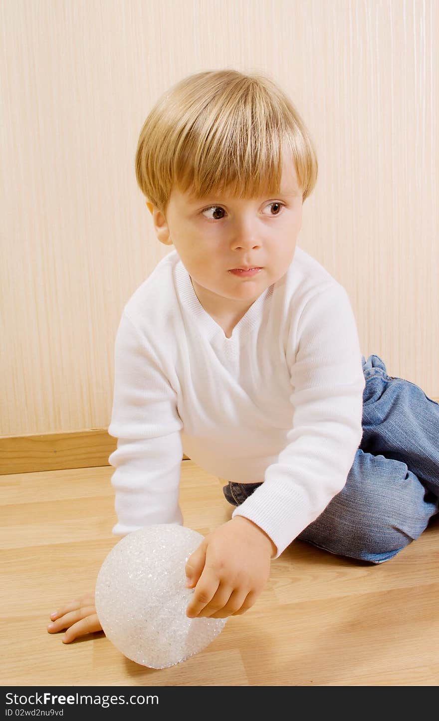 The child on the wood floor with white ball. The child on the wood floor with white ball