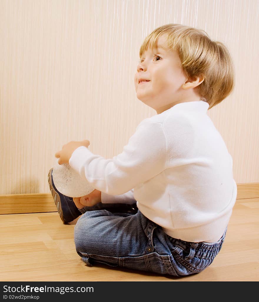 The child playing on the wood floor with white ball. The child playing on the wood floor with white ball