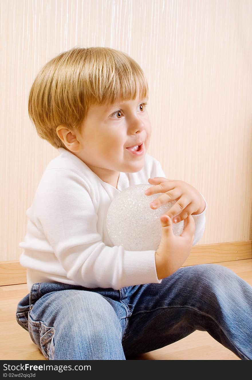 The child sitting on the wood floor with white ball. The child sitting on the wood floor with white ball