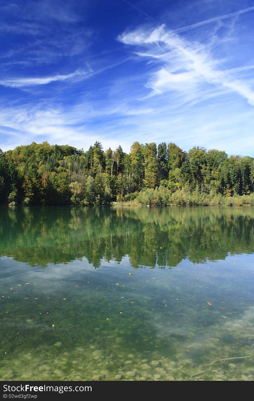 Green lake with colorful wood and blue sky in autumn. Green lake with colorful wood and blue sky in autumn