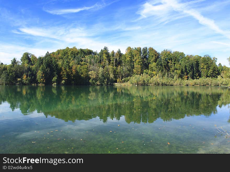 Green lake with colorful wood and blue sky in autumn. Green lake with colorful wood and blue sky in autumn