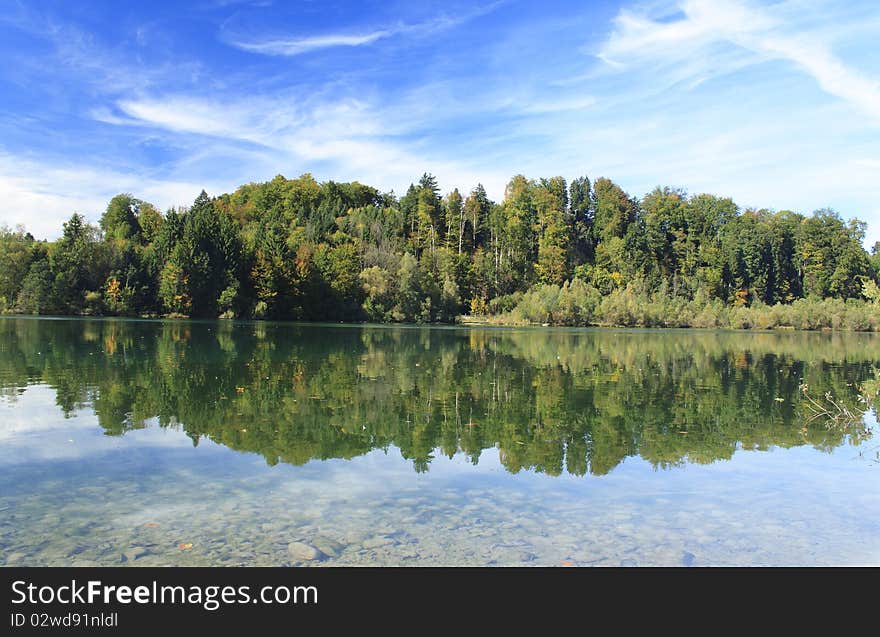 Green lake with colorful wood and blue sky in autumn. Green lake with colorful wood and blue sky in autumn