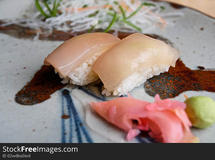 Japanese sushi with aquid and rice served with ginger and wasabi on a colorful pottery plate. Japanese sushi with aquid and rice served with ginger and wasabi on a colorful pottery plate.