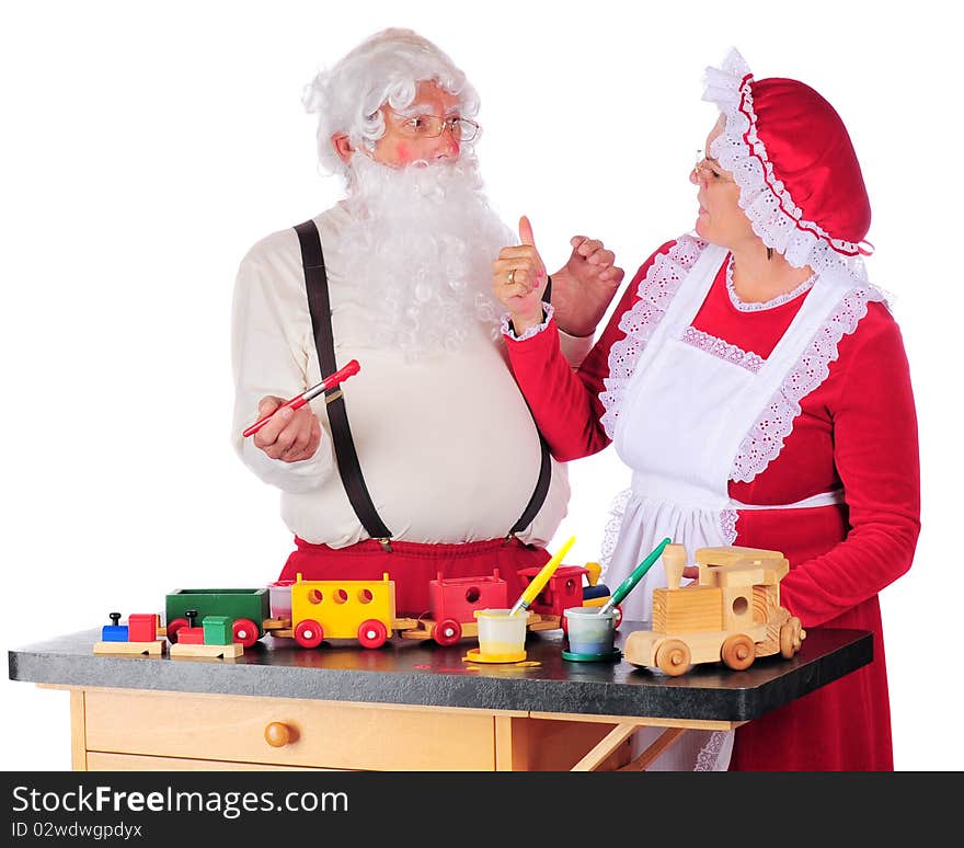 Mrs. Claus giving Santa a thumbs-up for the paint-job on the wooden train he's been working on for Christmas giving.  Isolated on white. Mrs. Claus giving Santa a thumbs-up for the paint-job on the wooden train he's been working on for Christmas giving.  Isolated on white.