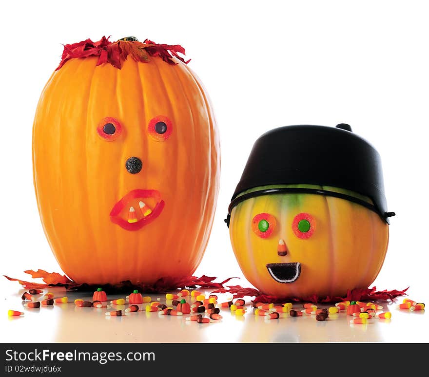 Two candy-faced pumpkins among scattered Halloween candy.  Isolated on white. Two candy-faced pumpkins among scattered Halloween candy.  Isolated on white.