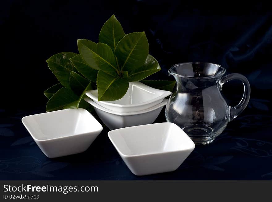 Containers in white ceramic pitcher and glass on a dark background. Containers in white ceramic pitcher and glass on a dark background